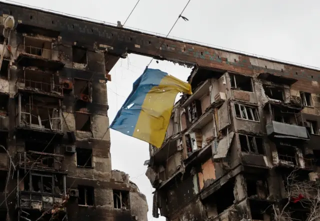 A view shows a Ukrainian flag near a destroyed building in Mariupol on 14 April 2022