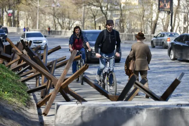 People pass the anti-tank hedgehogs in downtown Kyiv, Ukraine, 15 April 2022