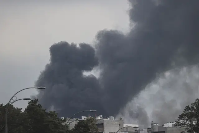 Clouds of thick black smoke are seen rising over the Darnytskyi district of Kyiv