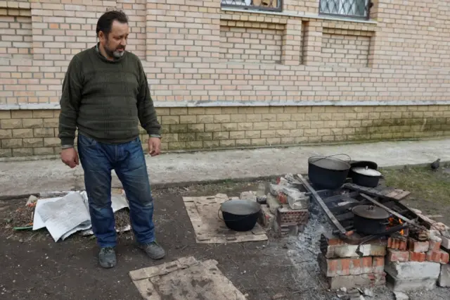 A local resident prepares food on a street, as Russia's attack on Ukraine continues, in Sievierodonetsk, Luhansk region,