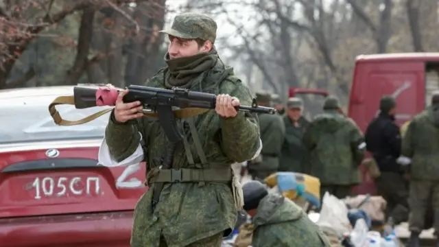 Service members of pro-Russian troops gather in a street in the southern port city of Mariupol