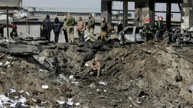 Ukrainian servicemen and rescuers inspect the site of military strikes on buildings as Russia's attack on Ukraine continues