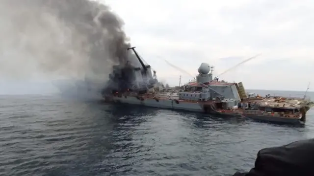 A photo apprently showing a damaged Russian warship billowing smoke and tilting to one side in the water