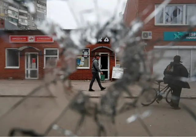 A local resident is seen through a broken window in Mariupol