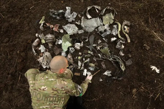 A Ukrainian soldier lays out fragments of a Russian missile that hit Kramatorsk