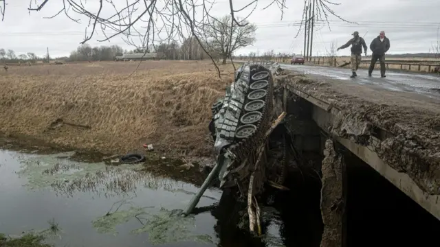 A damaged Russian tank lies next to a bridge in the Chernihiv region