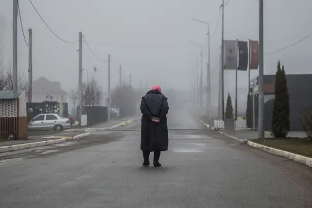 A woman walks along an empty street in Bucha, 1 April