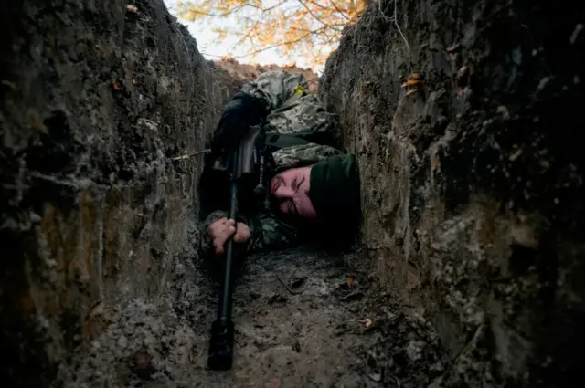 A Ukrainian soldier hides from a helicopter airstrike