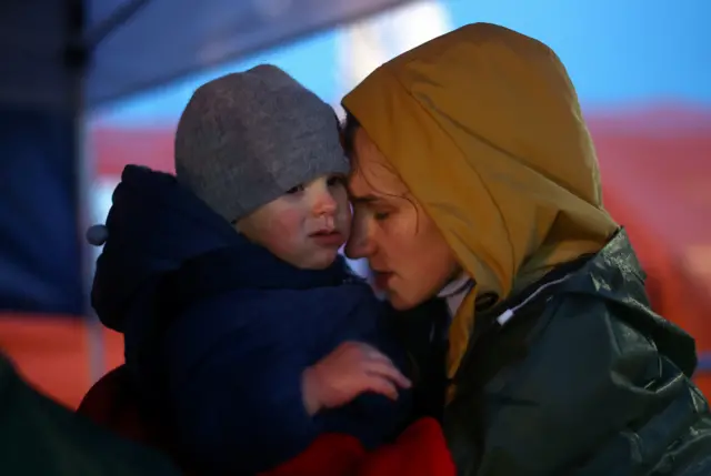 Ukrainian refugees shelter from the rain as they wait to a board a bus, bound for Przemysl after crossing the Ukraine-Poland border, amid the Russian invasion of Ukraine, in Medyka, Poland, 1 April 2022