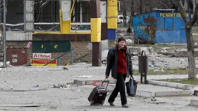 A man walks near a damaged building in Mariupol