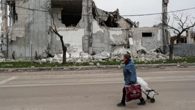 A local resident walks past a destroyed building in Mariupol