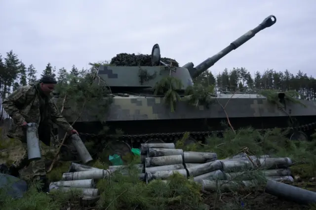 A service member of the Ukrainian armed forces carries an empty shell from a self-propelled howitzer at positions following Russia's invasion of Ukraine, near the settlement of Makariv, Ukraine, March 6, 2022