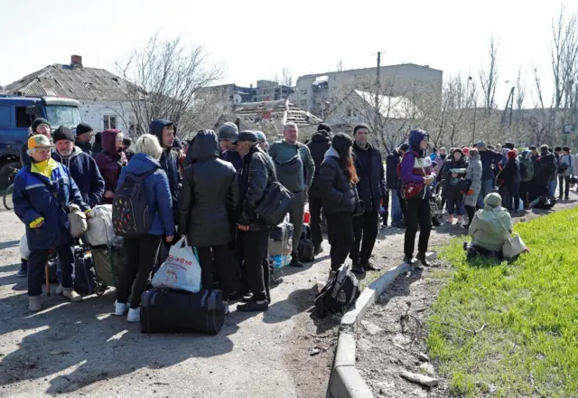 Evacuees wait before boarding a bus to leave embattled Mariupol