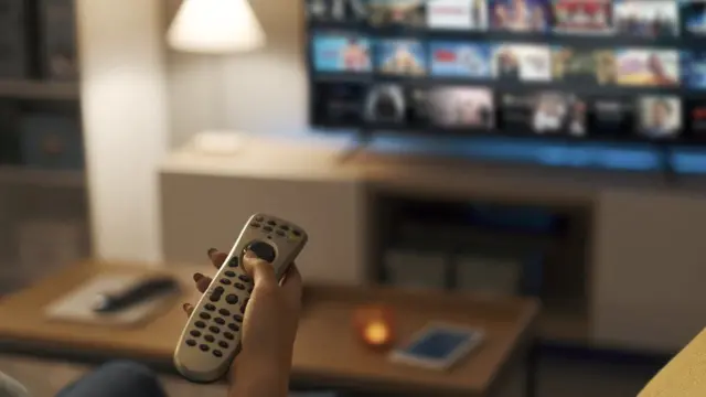 Person holds remote up to a TV