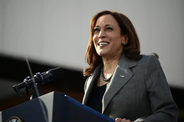 VP Harris smiling in front of a microphone