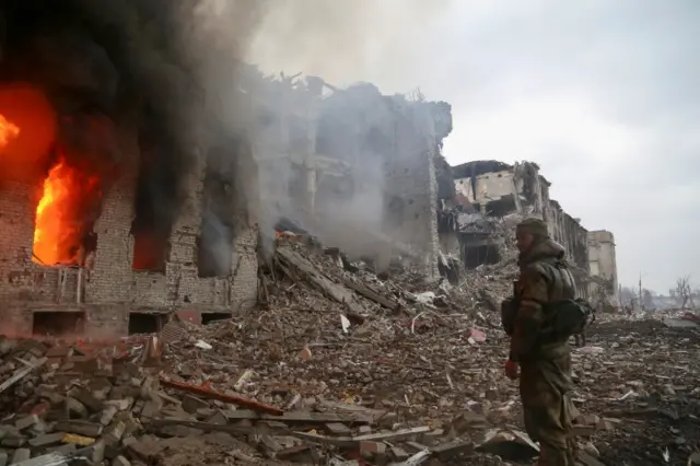 Pro-Russian fighter stands in front of the destroyed administration building of Azovstal steelworks