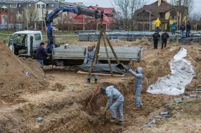 Forensic technicians exhume the bodies of civilians who Ukrainian officials say were killed during Russia's invasion and then buried in a mass grave in the town of Bucha