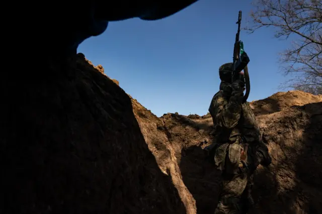 A Ukrainian sergeant walks through trenches on the front line in the Kherson region