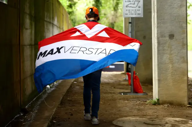 Max Verstappen fan walks with a flag over their back to the Imola circuit