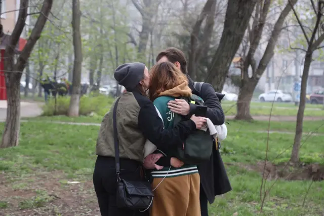 Image shows three people hugging