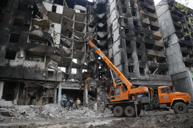 Heavy machines work by a destroyed building in the port city of Mariupol where the Russian army has taken control, on 22 April 2022