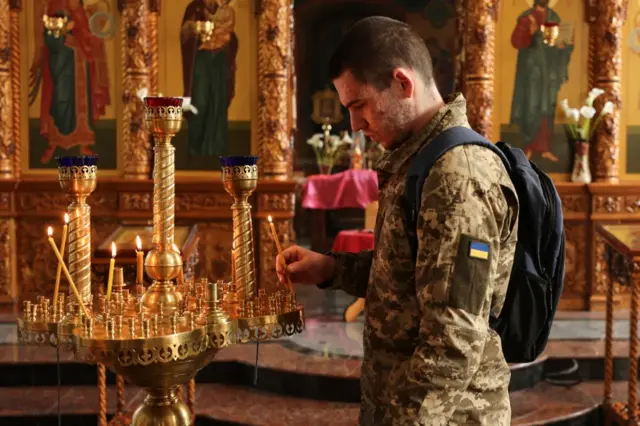 A Ukrainian serviceman with a lit candle inside a church