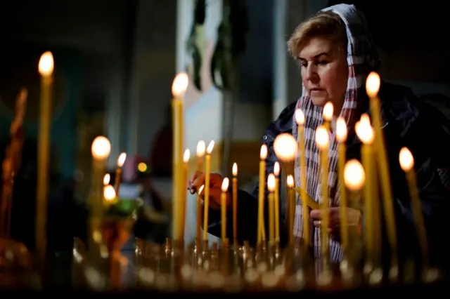 A woman lights a candle at the Cathedral of the Holy Trinity in Zaporizhzhia, south-eastern Ukraine. Photo: 24 April 2022