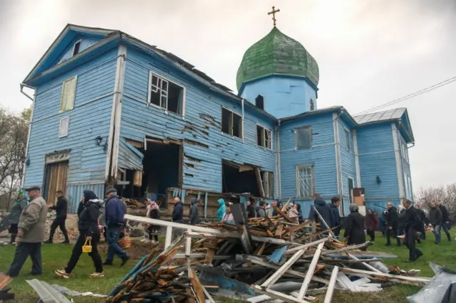 People walk after the Easter service next to The Nativity of the Holy Virgin Church damaged by Russian shelling in the village of Peremoha, Kyiv region. Photo: 24 April 2022