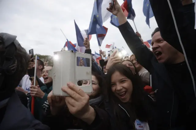 Happy Macron supporters cheering and waving flags