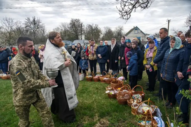 An Orthodox priest is joined by a soldier and worshippers for an Easter service