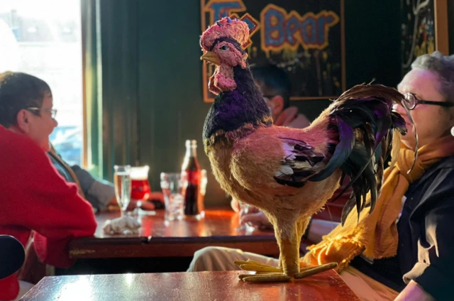 A toy cockerel on a table at a cafe table