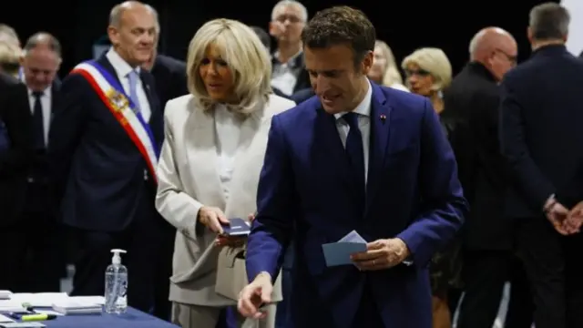 French President Emmanuel Macron, candidate for his re-election, and his wife Brigitte Macron take ballots to vote in the second round of the 2022 French presidential election, at a polling station in Le Touquet, France, 24 April 2022