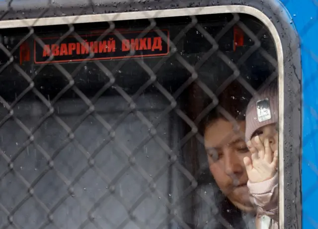 A Ukrainian refugee child looks out through a window labelled 'emergency exit' in Ukrainian