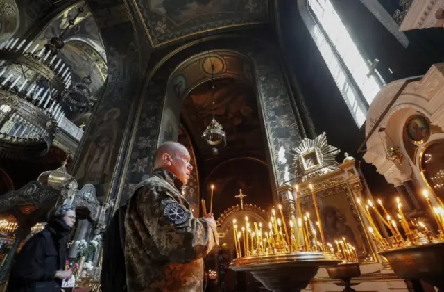 Civilians as well as military personnel light candles during an Easter service at St Volodymir Cathedral in Kyiv. Photo: 24 April 2022