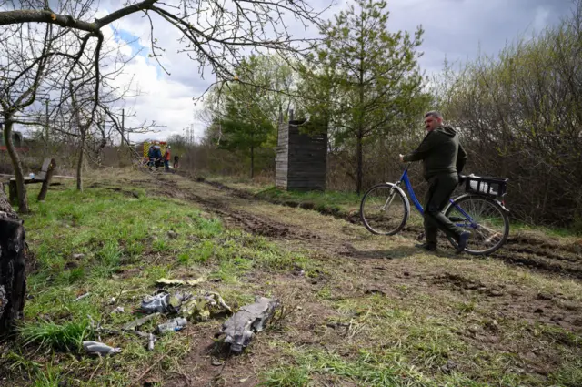 A resident looks at a pile of twisted metal from a Russian rocket near a train line on April 25, 2022 near Lviv, Ukraine.