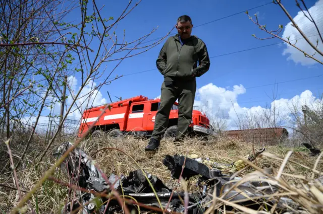 A resident looks at shards of twisted metal from a Russian rocket in undergrowth near a train line on 25 April 2022 near Lviv, Ukraine