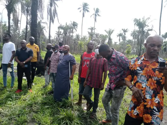 People gather for the mass burial near the scene of the blast in Egbema.