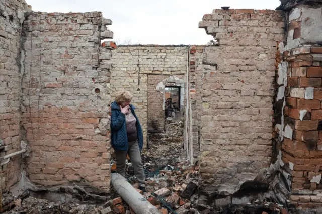 A woman stands in the ruins of her home in the Kyiv suburb of Ozera