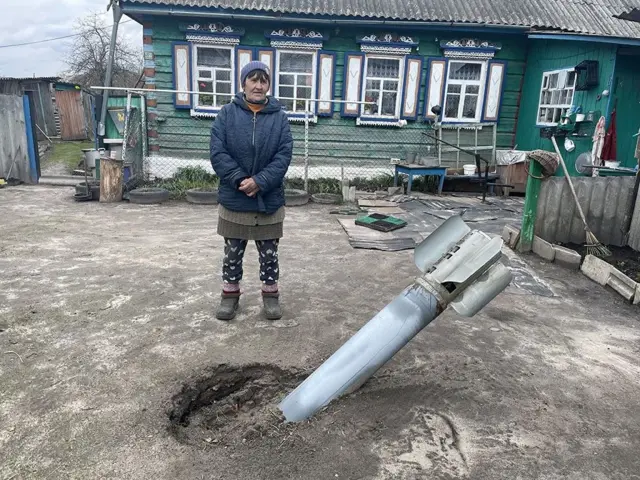 Ukrainian woman stands in garden next to missile