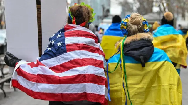 A man and woman wearings the flags of Ukraine and the US