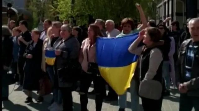 Protesters in Kherson's central square, holding an Ukrainian flag