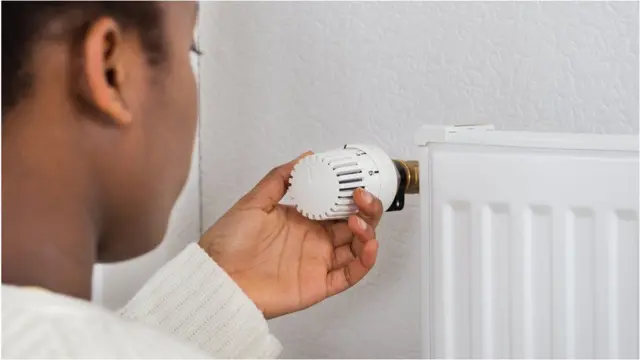 A person turning down the thermostat on a radiator