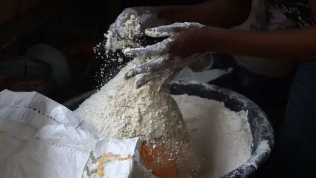 A vendor measures wheat flour in a cup at a market in Ibafo, Ogun State, southwest Nigeria - 14 March 2022