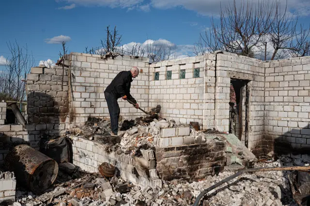 A person cleans the rubble of their home outside Kyiv