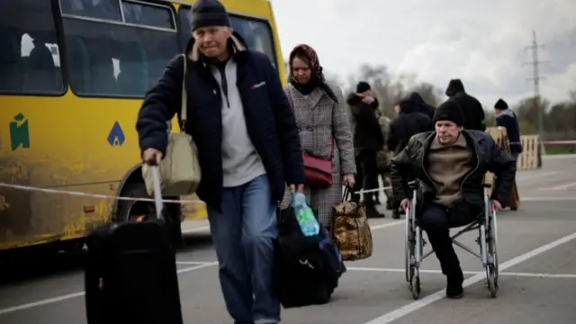 Ukrainian refugees from Mariupol area walk after arriving in a small convoy that crossed through a territory held by Russian forces