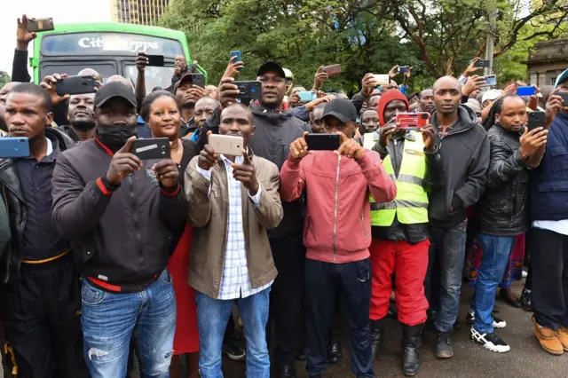 People take photos and react as the casket of former Kenyan President Mwai Kibaki passes on the way to a memorial service at the Nyayo National Stadium in Nairobi - 29 April 2022