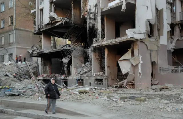 A woman walks past a building damaged in a missile strike in Kyiv