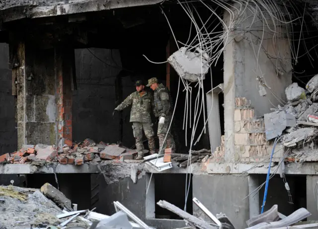 Soldiers inspect a damaged building