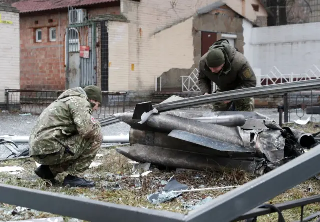 Police officers inspect the remains of a missile that fell in the street in Kyiv