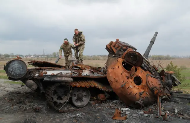 Ukrainian troops inspect a destroyed Russian tank